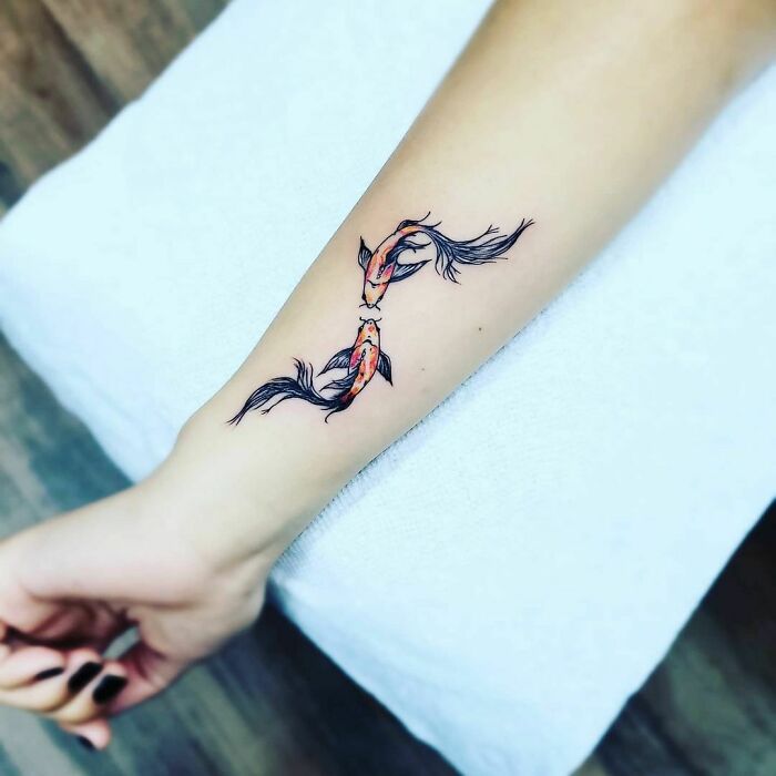 Beautiful watercolor tattoo of two koi fish on an arm, showcasing elegant and intricate ink design.