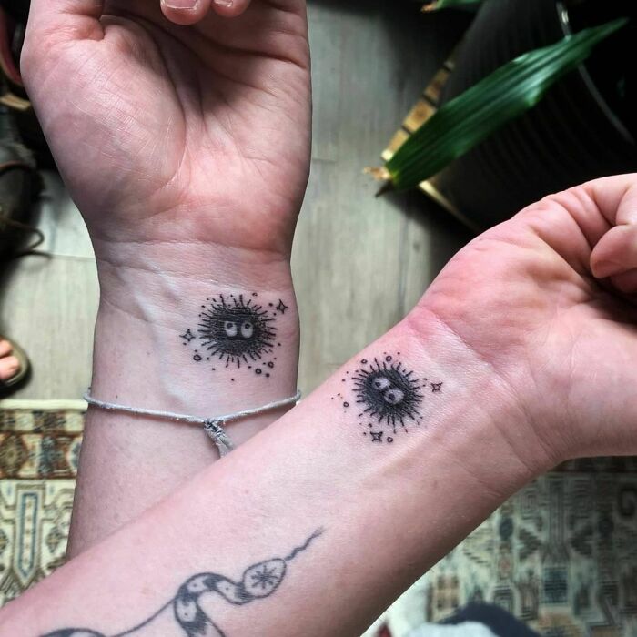 Matching BFF tattoos on wrists, featuring sunburst eyes, symbolizing friendship and togetherness.