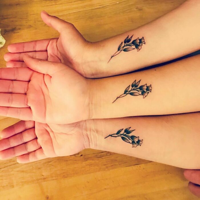 Three matching floral tattoos on forearms symbolize brother and sister connection.