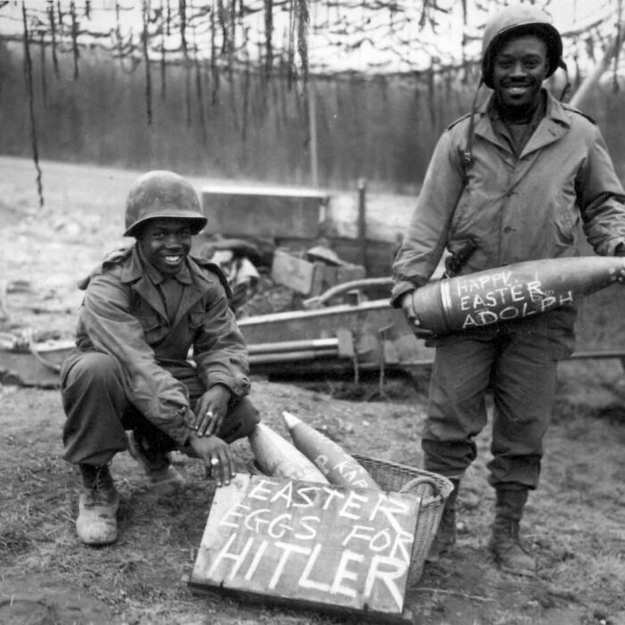 Two men holding an infantry shells with sunny messages on them 