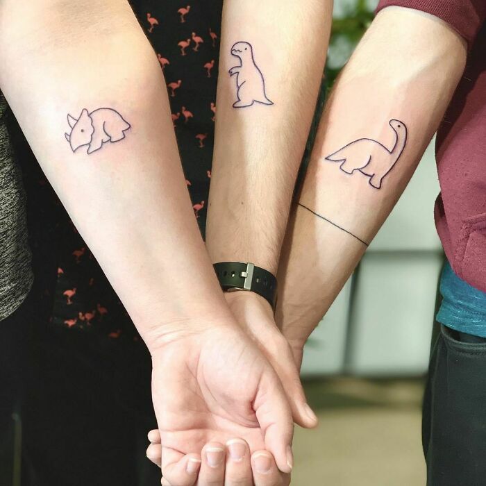 Brother and sister tattoos featuring matching dinosaur designs on forearms, symbolizing connection and unity.