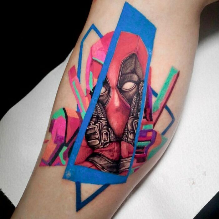 Marvel tattoo of Deadpool with colorful geometric shapes on arm.