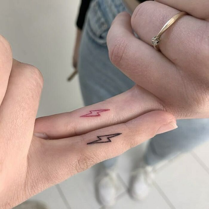 Close-up of two fingers with matching lightning bolt tattoos, symbolizing best friends.