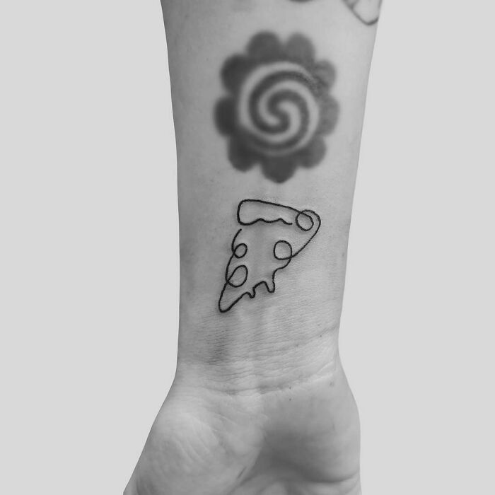 Fine-line single-line tattoo of a pizza slice on a person's forearm.