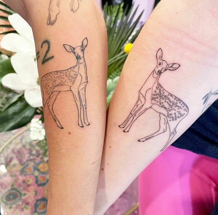 Matching deer tattoos on arms symbolizing friendship.