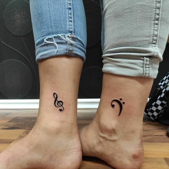 BFF tattoos featuring a treble clef and bass clef on friends' ankles, symbolizing their musical bond.