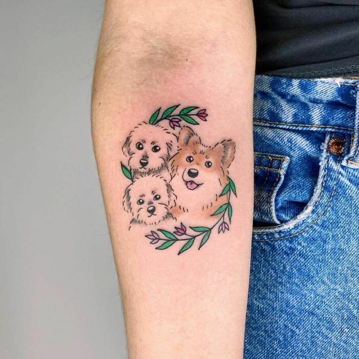 Pet tattoos featuring three adorable dogs with floral accents on forearm, celebrating furry friends.