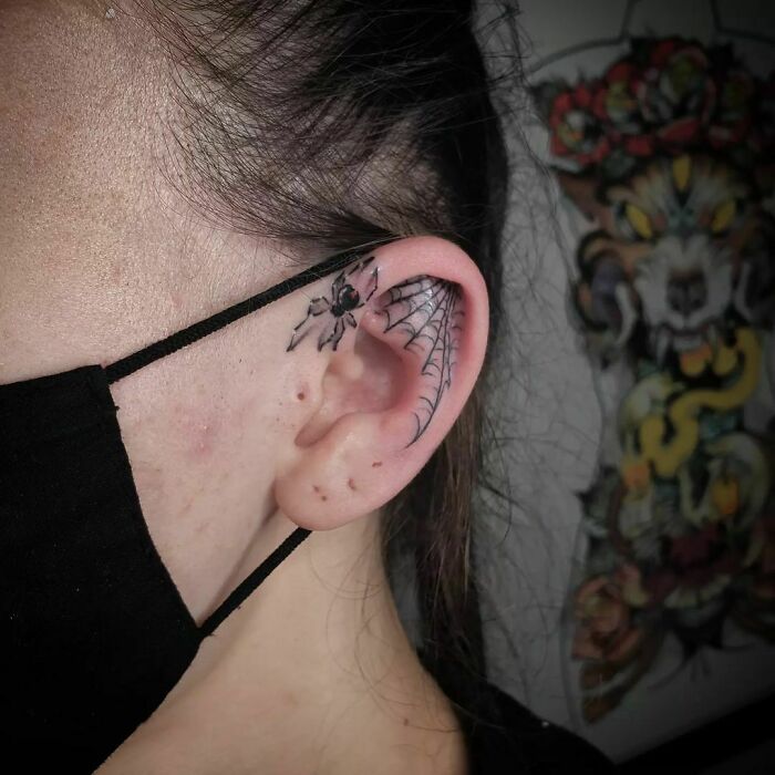 Spider web ear tattoo design with a realistic spider, showcasing creative ear tattoo ideas.