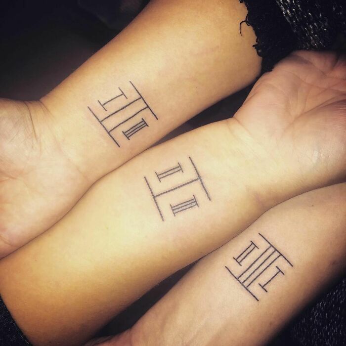 Brother and sister matching Roman numeral tattoos on wrists symbolizing unity.
