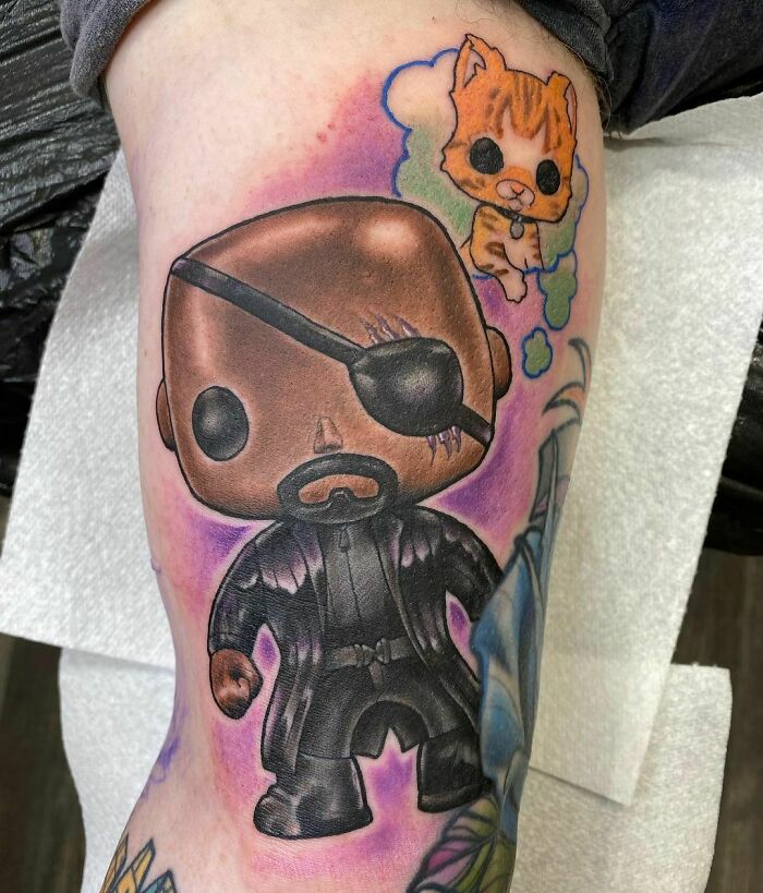 Marvel tattoo featuring a fun character with an eye patch and an orange cat, on a vibrant background.