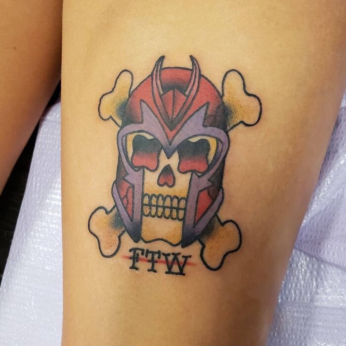 Colorful Marvel tattoo featuring a skull with a red helmet and crossed bones.