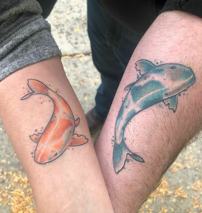 Two arms with complementary fish tattoos symbolizing best friend tattoos, depicting colorful koi carp in motion.