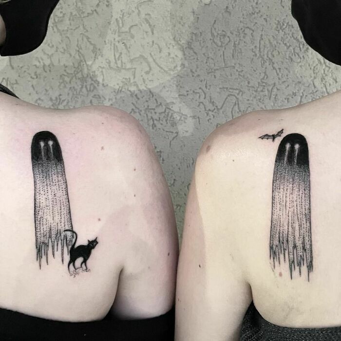 Best friend tattoos on shoulders featuring abstract ghost designs and a black cat and bat, symbolizing friendship.