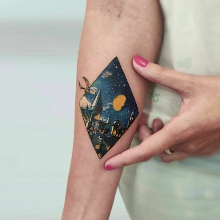 Harry Potter tattoo featuring a colorful Hogwarts scene and Golden Snitch on forearm.