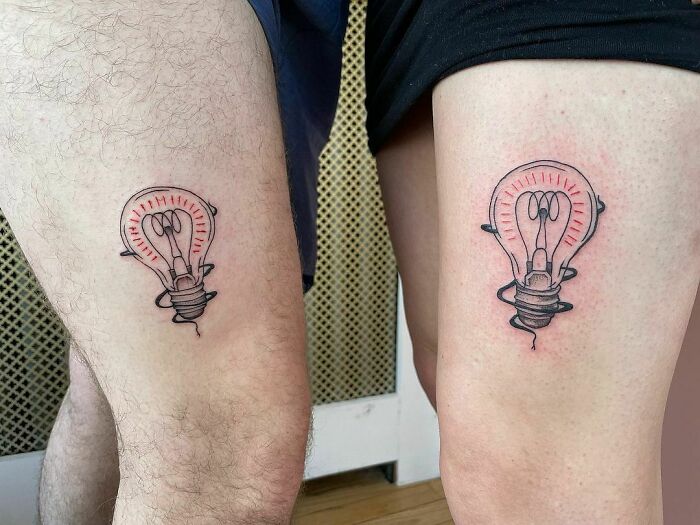 Matching light bulb friend tattoos on thighs, symbolizing a bright friendship.