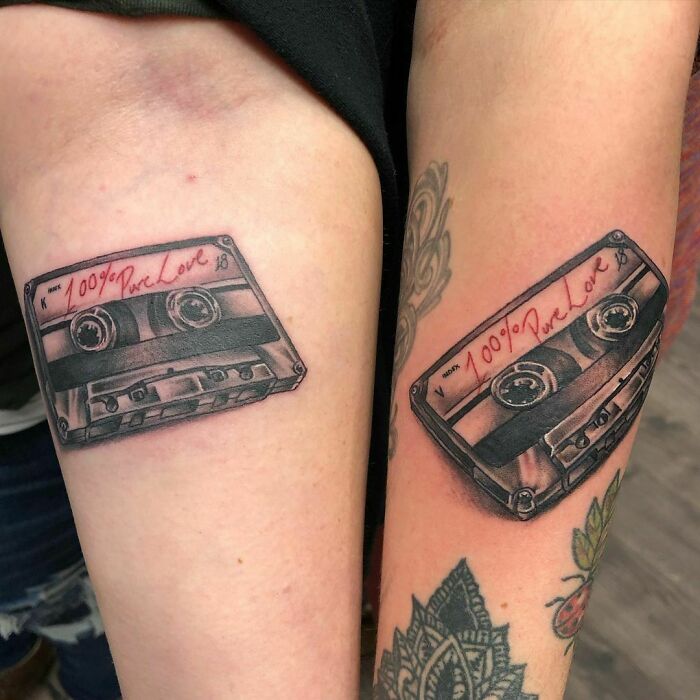 Cassette tape tattoos on arms symbolizing best friend bond and shared memories.