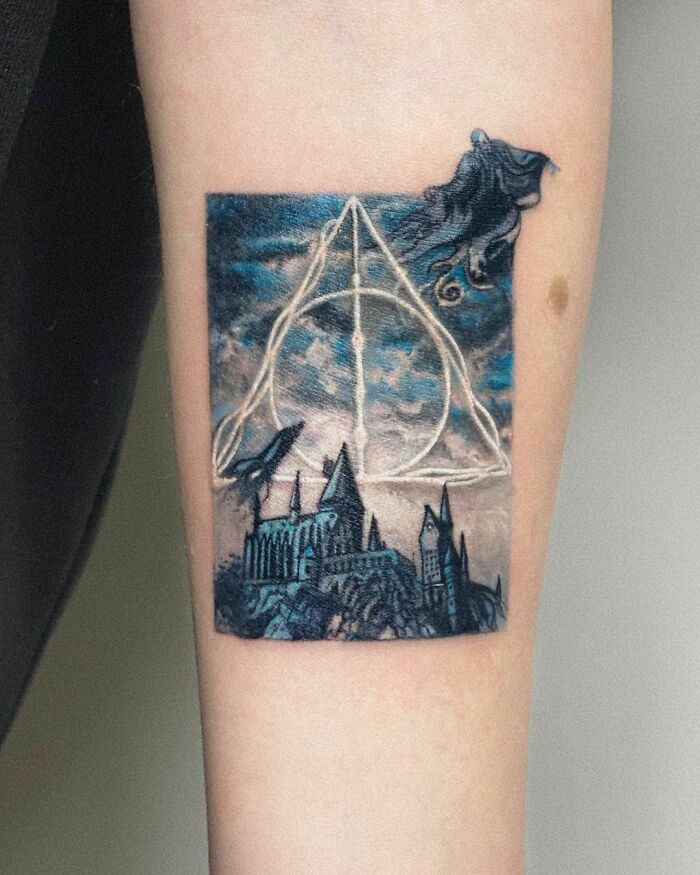 Harry Potter tattoo featuring the Deathly Hallows symbol and Hogwarts castle on forearm.