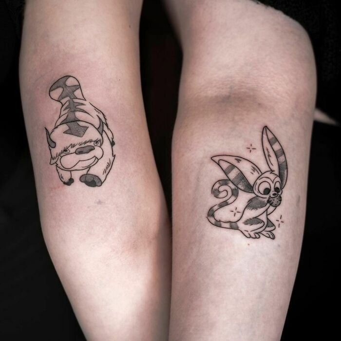 Matching friend tattoos featuring cartoon animals, symbolizing friendship.
