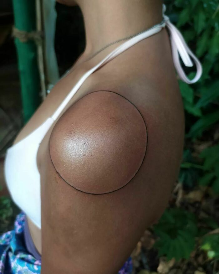 A fine-line tattoo with a single-line circle on a shoulder, showcasing minimalist tattoo art.
