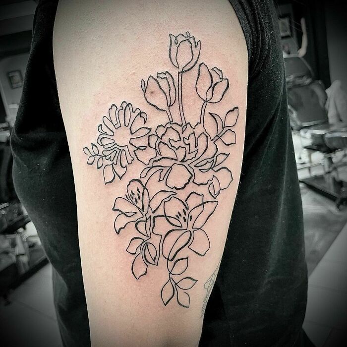 Floral single-line tattoo on arm, featuring roses and lilies in elegant black ink design.
