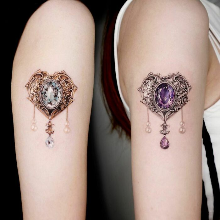 Intricate best friend tattoos with ornate designs and gemstone details on inner arms, symbolizing deep friendship.