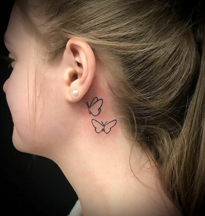 Butterfly ear tattoo with simple line design behind woman's ear, showcasing unique ear tattoo ideas.