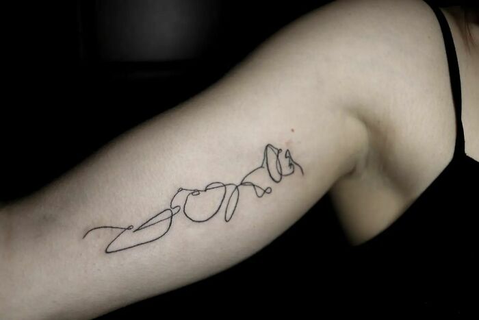 Fine-line single-line tattoo on an arm showcasing intricate design.