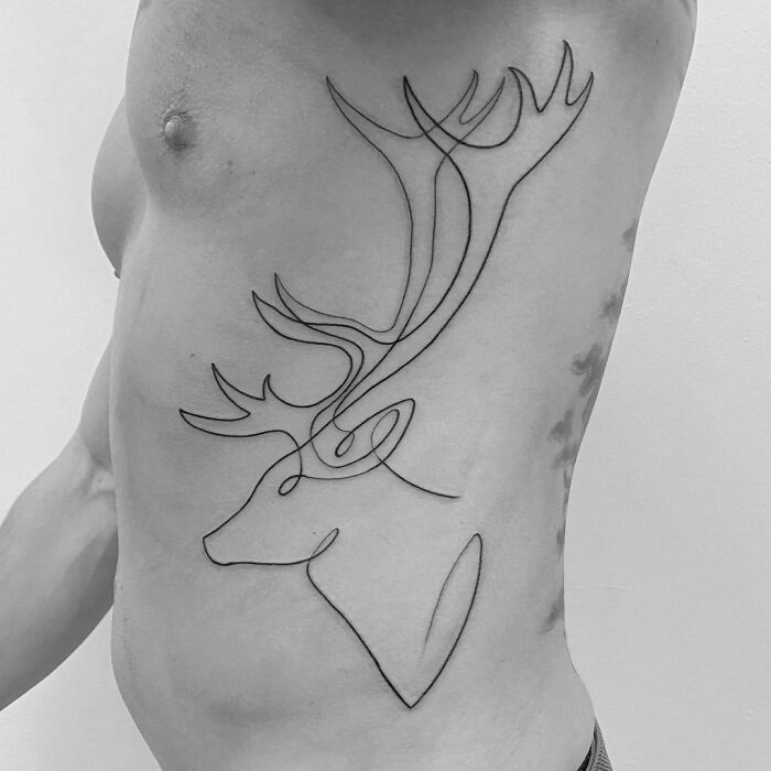 Single-line tattoo of a stag with antlers on a person's side, showcasing minimalist ink art.