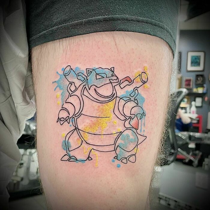 Single-line tattoo of a cartoon character with colorful splashes on an arm, showcasing fine-line perfection.