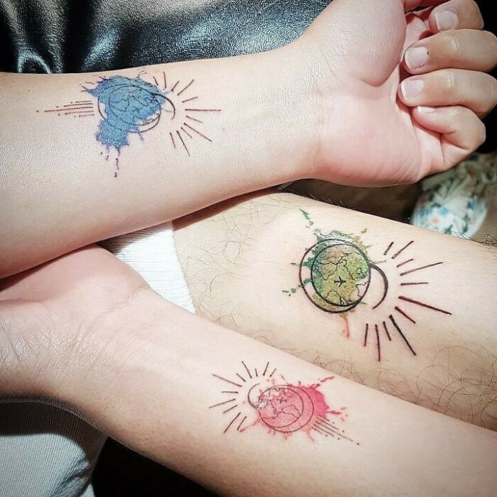 Brother and sister tattoos featuring colorful planets and crescents on forearms, symbolizing unity and connection.