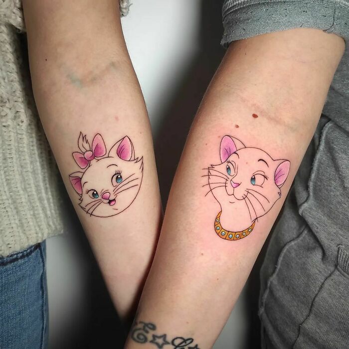 Cartoon tattoos of two cats on forearms, inspired by childhood favorites.