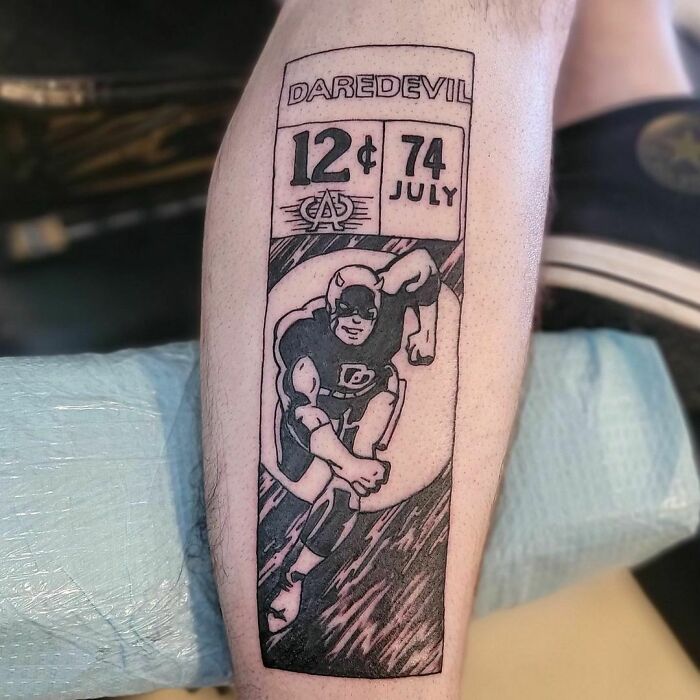 Marvel tattoo of Daredevil comic cover on a leg, showcasing vintage design elements.