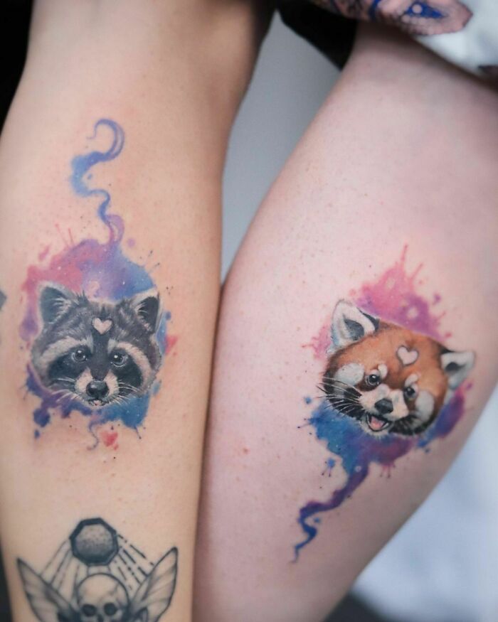 Watercolor style best friend tattoos of raccoon and red panda on arms, symbolizing close friendship.