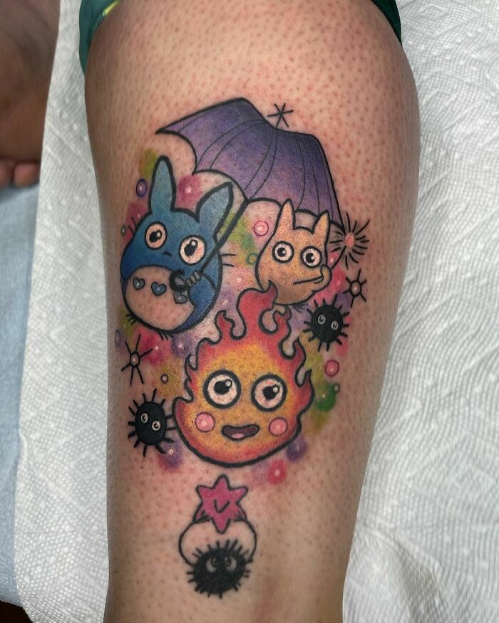 Colorful cartoon tattoo featuring characters from popular animated shows, including creatures with an umbrella and flames.