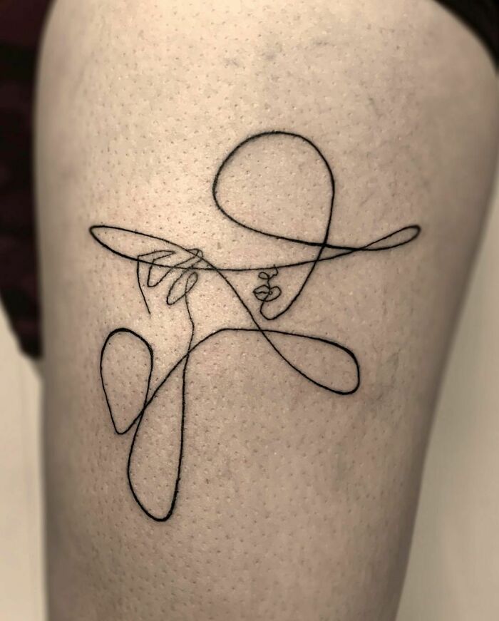 Minimalist single-line tattoo of an abstract human figure on skin.