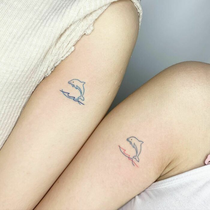 Matching dolphin tattoos on two arms, symbolizing best friend tattoos for lasting friendship.