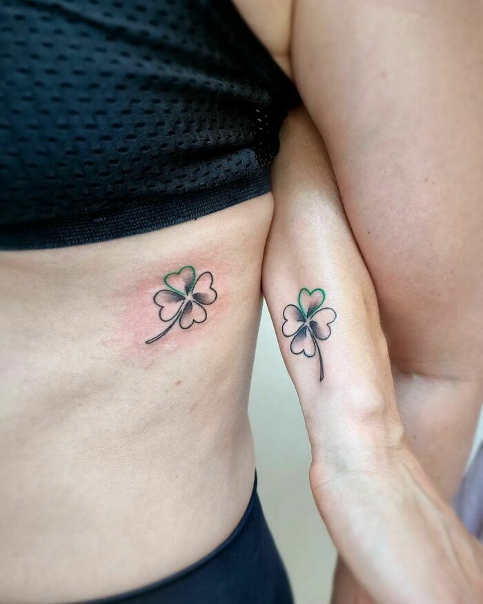 Brother and sister clover tattoos on their sides, symbolizing kinship and simplicity.
