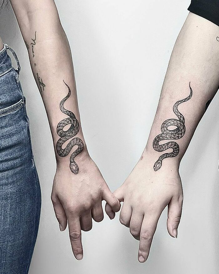 Matching snake tattoos on sibling forearms, symbolizing brother and sister connection.