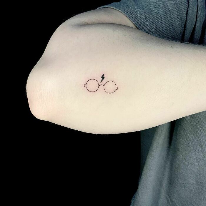 Tattoo of Harry Potter's glasses and lightning bolt on an arm, perfect for wizarding world fans.