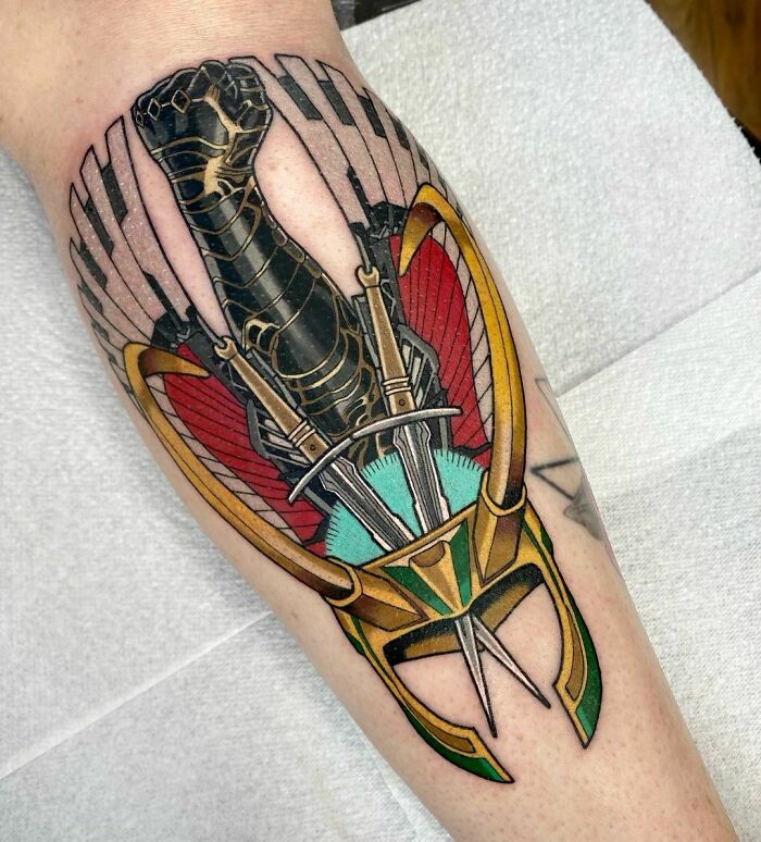 Marvel tattoo featuring a stylized arm and helmet design with bold colors on a forearm.