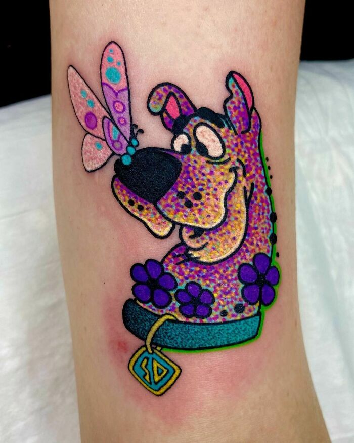 Cartoon tattoo of Scooby-Doo with a butterfly on his nose, evoking nostalgia.