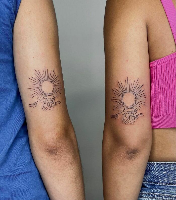 Brother and sister small tattoos of a sun with hands, symbolizing connection and unity, on their upper arms.