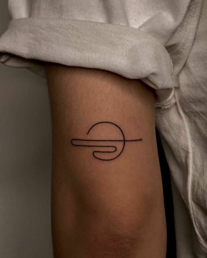 Minimalist line tattoo on forearm, featuring a simple abstract design.