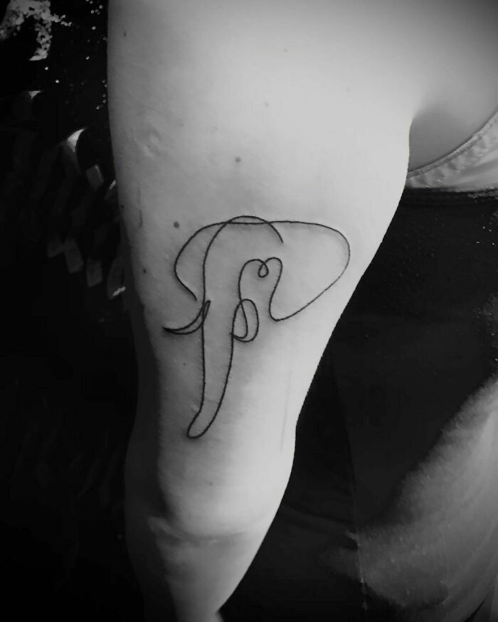 Minimalist tattoo of an elephant created with a single line on an arm.