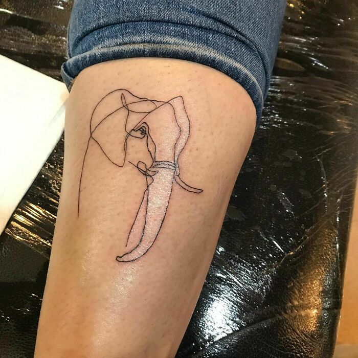 Fine-line single-line tattoo of an elephant on a person's leg.