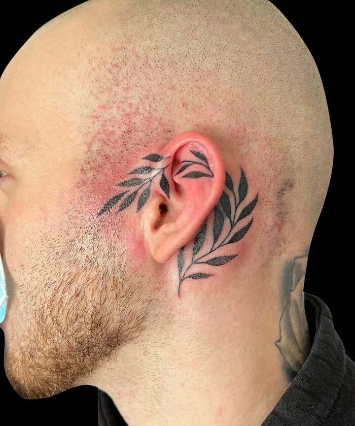 Bald person with leaf pattern ear tattoo.