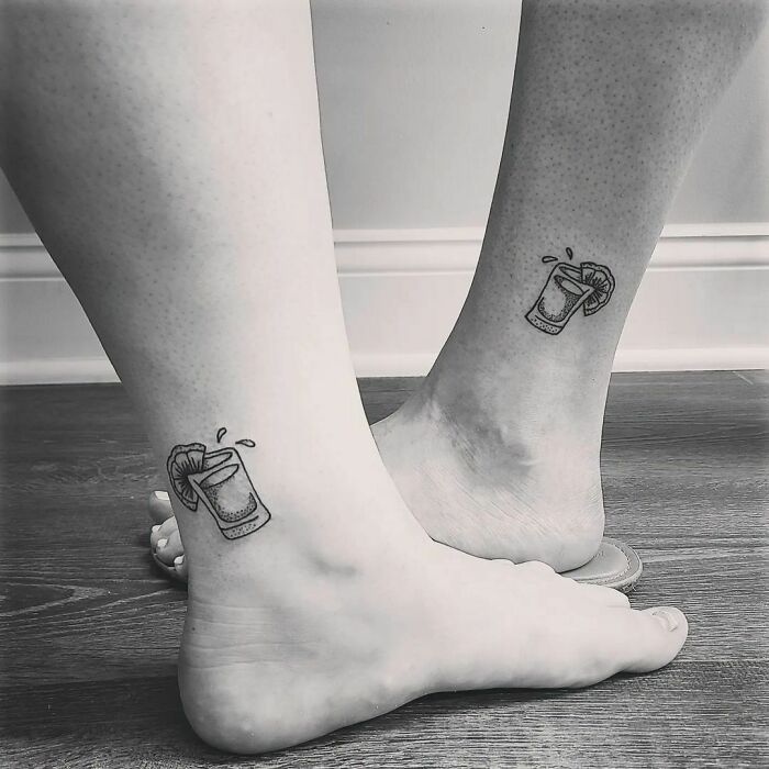 Matching best friend tattoos of juice glasses on ankles, symbolizing friendship.