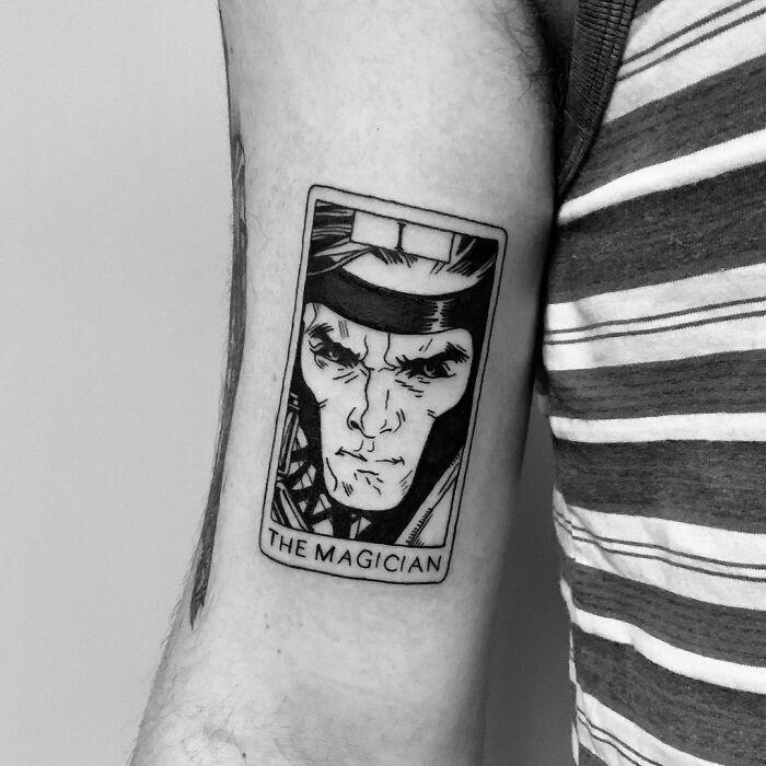 Marvel tattoo with "The Magician" design on an arm, featuring bold black line art.
