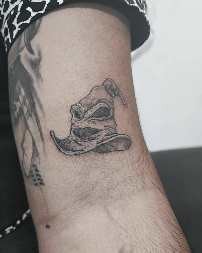Harry Potter tattoo of the Sorting Hat on a person's arm, showcasing intricate black ink design.
