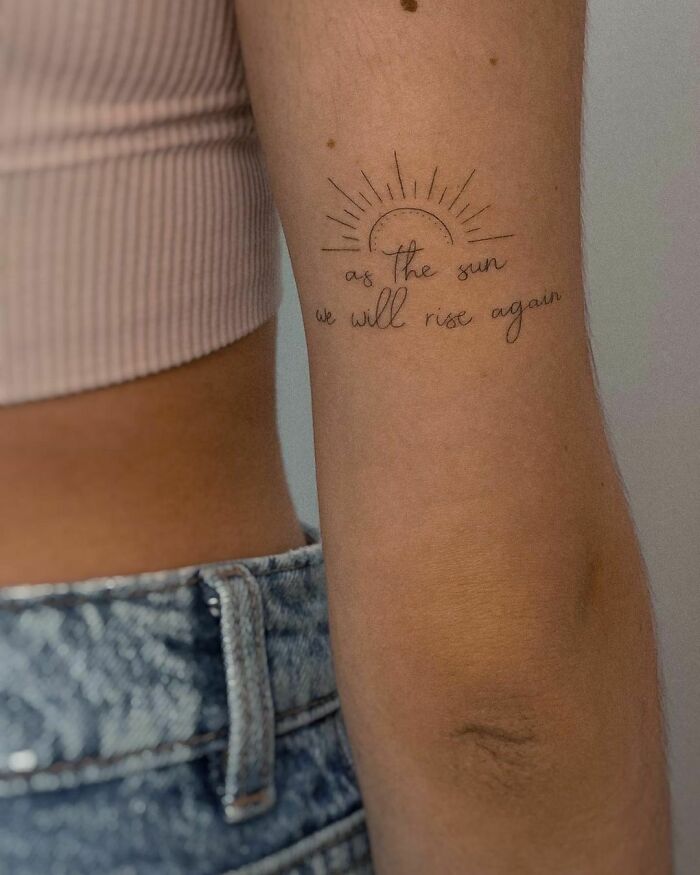 Minimalist tattoo on arm with a sun and inspirational words, showcasing word tattoos that speak to your heart.